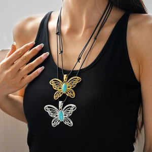 Detailed view of hollow butterfly filigree pendant necklaces with blue gemstone accents