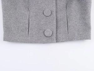 Detailed view of grey wool-blend fabric with fabric-covered buttons and clean hem stitching