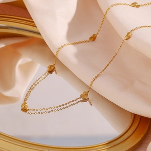 Detailed shot of gold heart charms with radial textures on a delicate steel chain