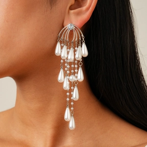 Close-up of model wearing long silver tassel earrings with zircon and teardrop pearls