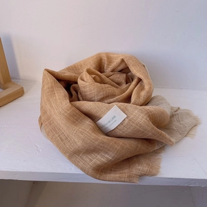 Close-up of caramel gradient cotton linen scarf with elegant fringe and woven label