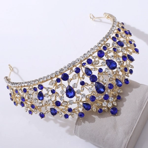 Close-up of gold crown featuring blue teardrop gems and intricate diamond engraving