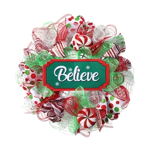 Close-up of Christmas wreath with red ribbons and Believe sign for festive wall decor