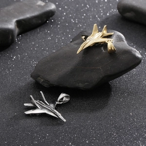 Detailed view of silver and gold fighter jet pendants on dark polished stones