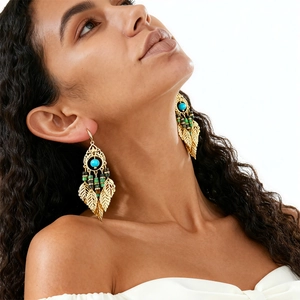 Boucles d'oreilles bohèmes en feuilles dorées et perles turquoise portées par un mannequin