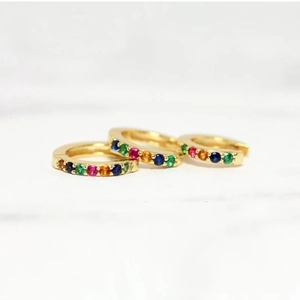 Macro shot of three gold hoop earrings featuring multi-colored rainbow zircon stones