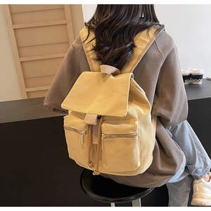 Vista trasera de modelo con mochila de lona mostaza con solapa y cordón ajustable