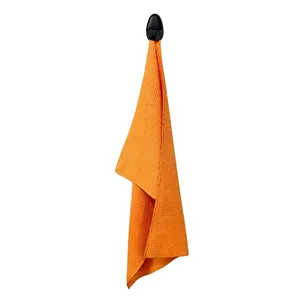 Detail of orange waffle weave golf towel with black magnetic hanging clip on white background