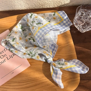 Detail of floral and blue plaid cotton linen headscarf on a wooden tray in natural light