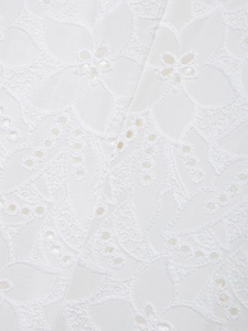 Détail macro de la broderie en dentelle blanche et motifs évidés du tissu du blazer