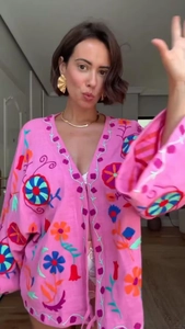 Close-up of pink embroidered cardigan featuring vibrant floral patterns and long sleeves