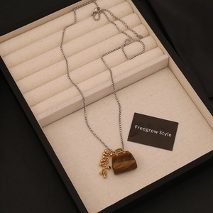 Macro shot of tiger eye stone handbag pendant on a delicate silver chain inside a box