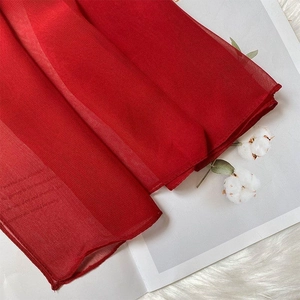 Detail of soft red silk scarf featuring a semi-transparent texture and elegant drape