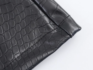 Close-up detail of crocodile embossed texture on black PU leather trench coat fabric