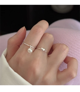 Close-up of 925 sterling silver heart ring and pearl pendant on a model's hand