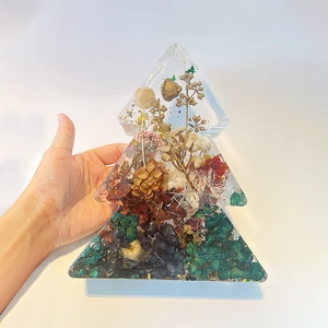 Detail of a Christmas tree resin ornament filled with dried flowers and gold bells