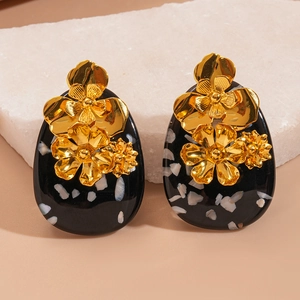 Detailed macro view of vintage oval resin earrings with gold flower on marble