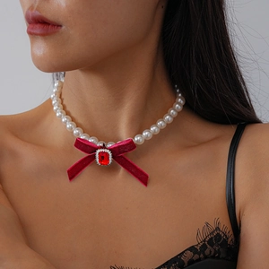 Detail of white pearl necklace featuring a vintage red velvet bow with square rhinestone