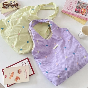 Close-up of waffle texture canvas tote bags with colorful bow embroidery and brand tag