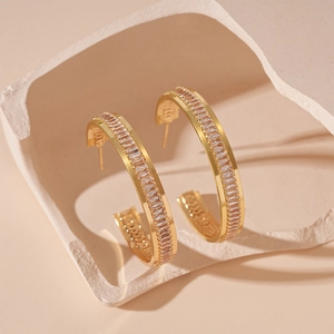 Close-up of gold geometric C-shaped earrings with channel-set baguette cubic zirconia
