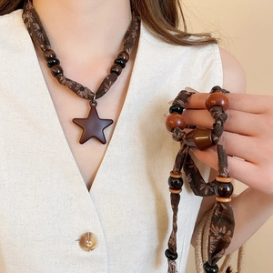 Détail de perles en bois et pendentif étoile sur un collier vintage en coton-lin