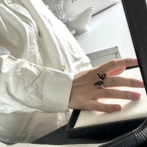 Detail of a handmade black beaded bow ring featuring a vintage woven style on finger
