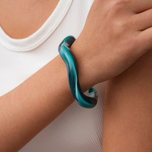 Detailed view of irregular geometric teal acrylic cuff bracelet worn on a wrist