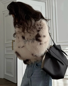 Detail of soft white leopard faux fur coat paired with a luxury black leather tote bag