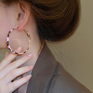Close-up of pink and black leopard print hoop earrings with golden metal edges