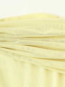 Macro view of light yellow mesh fabric with delicate pleated texture and layered tulle detail