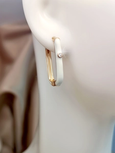 Close-up of gold-plated enamel hoop earring with a sparkling cubic zirconia on a model