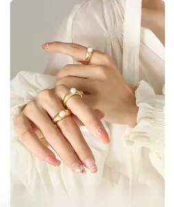 Detailed view of three French-style gold rings with white freshwater pearls on a model