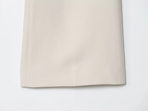 Gros plan sur la texture tissée et les coutures de l'ourlet du pantalon évasé blanc cassé