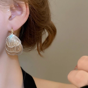 Golden layered hollow heart petal earrings with brushed metal texture worn by a model