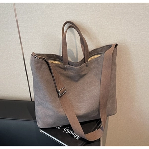 Detail of a deep brown large canvas tote bag with top handles and adjustable shoulder strap