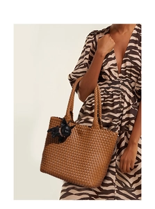 Close-up of brown woven leather tote bag with a cute black bulldog charm accessory