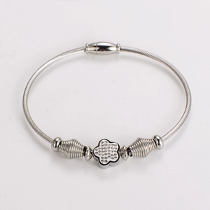 Detail of silver stainless steel cable bracelet with rhinestone floral charm