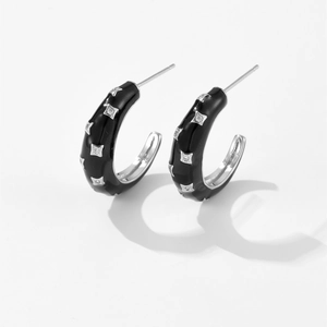 Detailed close-up of black C-shaped hoop earrings with square white zircon stones
