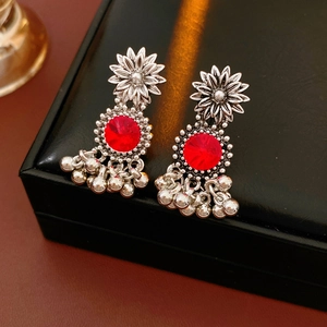 Detail of silver vintage earrings with red floral gemstones and hanging jhumka bells