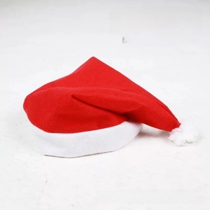 Close-up of non-woven fabric texture and white plush pom-pom on classic Red Christmas hat