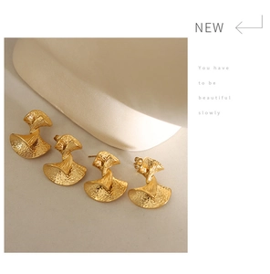 Detail showing vintage golden fan-shaped textured earrings with hammered metal spiral design
