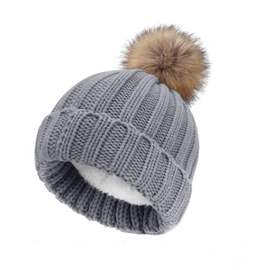 Detailed close-up of thick grey knit hat with warm white fleece lining and soft pompom