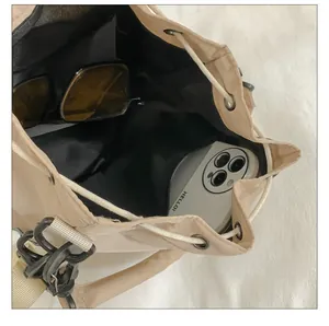 Interior view of beige nylon bucket bag showing storage for phone and sunglasses