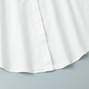 Detail shot of the curved hemline and premium cotton texture of the white shirt dress