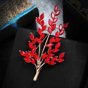 Macro shot of gold wheat brooch with red crystal leaves on a textured black box
