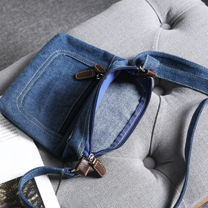 Detail view of denim crossbody bag showing high-quality zippers and spacious interior