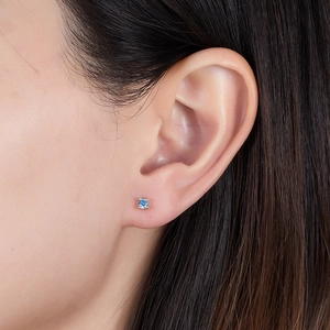 Close-up of golden S925 silver stud earring with square blue zircon in four-prong setting