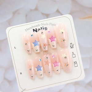 Detail view of handmade pink press-on nails with star patterns and sparkling rhinestones