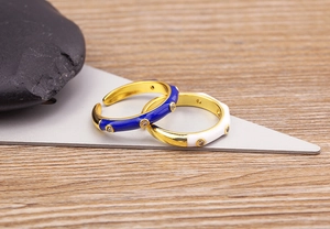 Detail of 18K gold plated brass rings with blue and white enamel and zircon accents