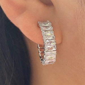 Gros plan de boucles d'oreilles créoles en C avec zircons carrés sur l'oreille